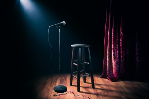 microphone and wooden stool on a stand up comedy stage with refl